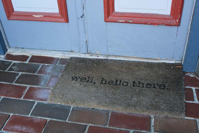 Stack of stylish doormats in natural fibers on a rustic wooden porch